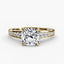 Gold ring with a large cushion cut diamond and smaller round diamonds on the band against a white background