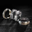 Four solid gold mens rings with textured designs on a dark surface
