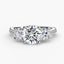 Three stone round diamond center stone two round sides engagement ring tapered micro pave setting on the shank white gold or platinum on a white background
