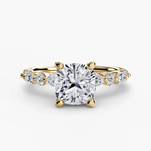 Gold ring with a large cushion cut diamond and smaller marquise shaped and round cut diamonds on the band against a white background