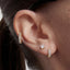 Close-up of an ear wearing gold hoop earrings and a stud earring.