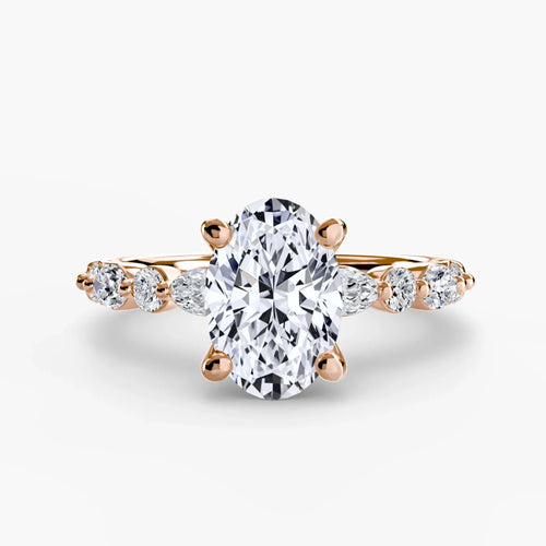 Rose gold ring with a large oval diamond and smaller marquise and round diamonds on the sides against a white background