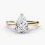 Solitaire gold ring with a pear-shaped diamond on a white background