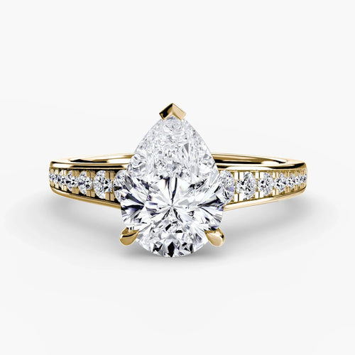 Gold ring with a pear-shaped diamond on a white background