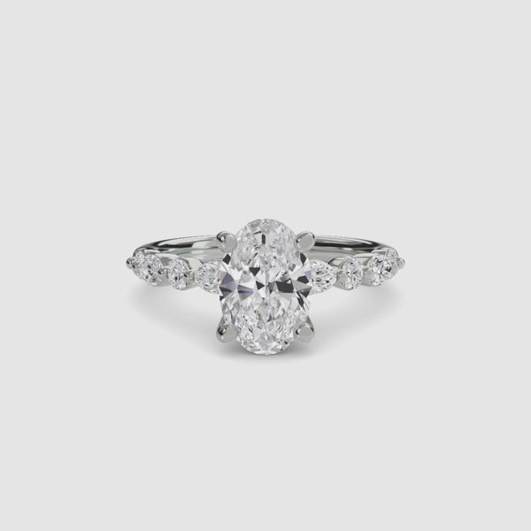 Diamond ring with a central oval-cut diamond and smaller round and marquise diamonds platinum on a white background
