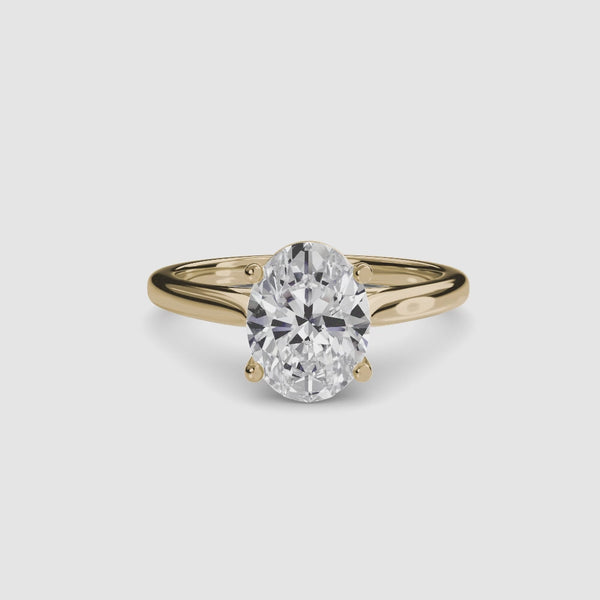 Solitaire gold ring with a large oval-cut diamond on a white background
