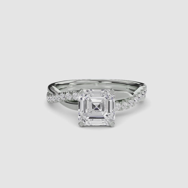 White Gold ring with a large Asscher diamond and smaller diamonds on the twisted band against a white background