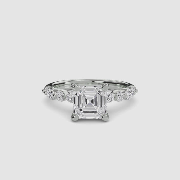White gold ring with a large Asscher-cut diamond and smaller diamonds on the band marquise and round on a white background