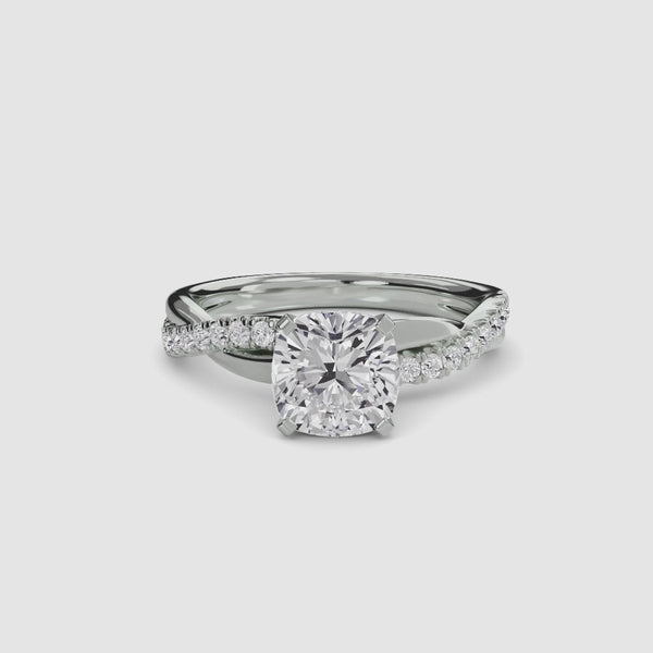 White gold ring with a large cushion-cut diamond and smaller diamonds on the twisted band against a white background