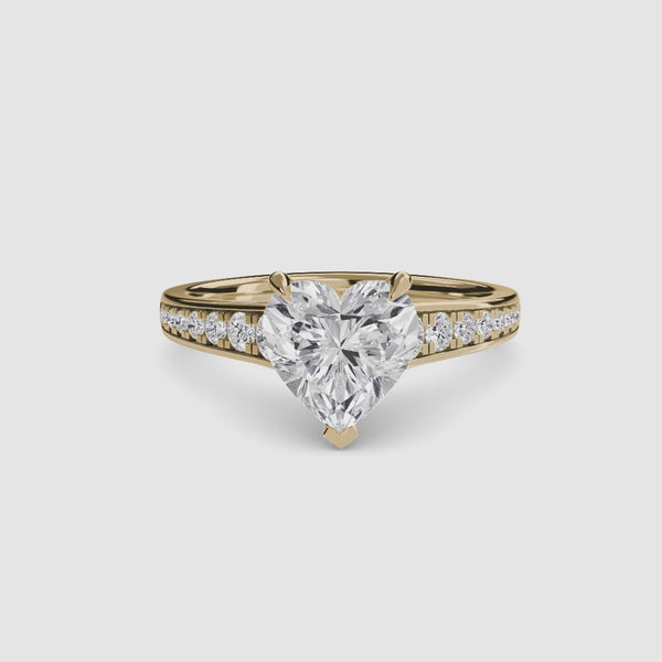 Gold ring with a heart-shaped diamond and round pave on the shank on a white background
