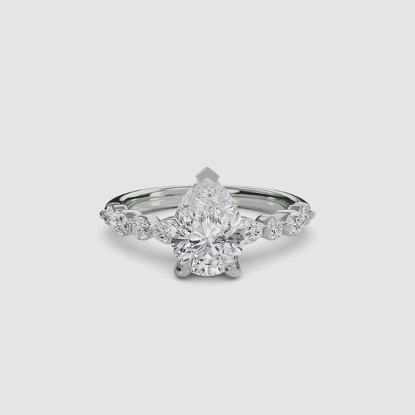 Pear shaped diamond ring with marquise and round side stones white gold on a white background