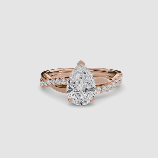 Rose gold ring with a pear-shaped diamond and twisted pave shank on a white background