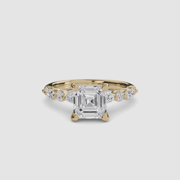Gold ring with a large Asscher-cut diamond and smaller diamonds on the band marquise and round on a white background
