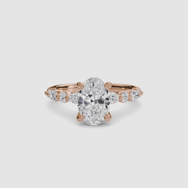Rose gold ring with a large oval diamond and smaller marquise and round diamonds on the sides against a white background