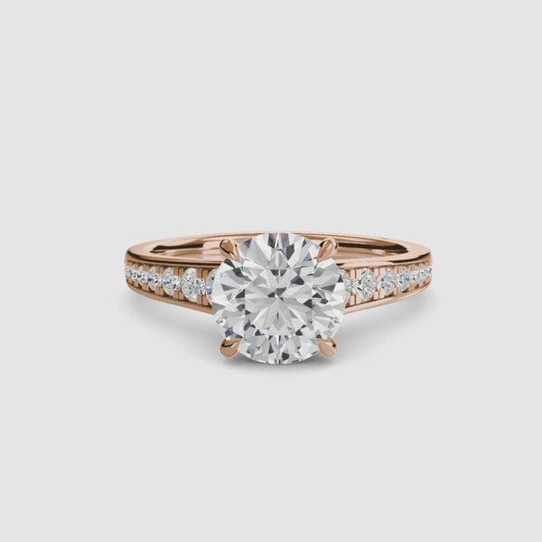 Rose gold ring with a large round diamond and smaller diamonds on the band against a white background