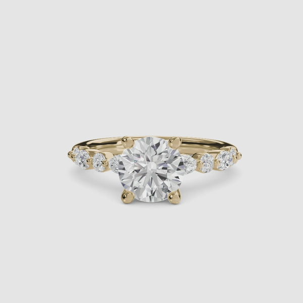 Gold ring with a large round diamond and smaller diamonds on the band against a white background