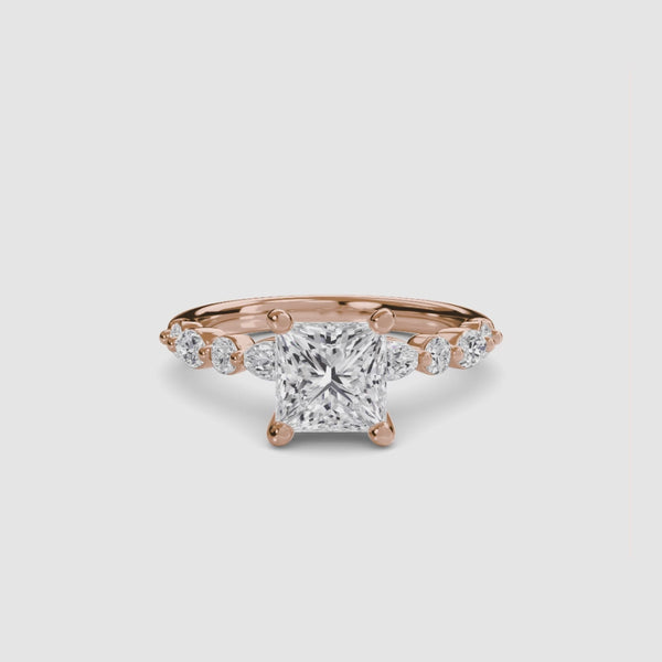Rose Gold ring with a large central princess diamond and smaller diamonds on the band against a white background