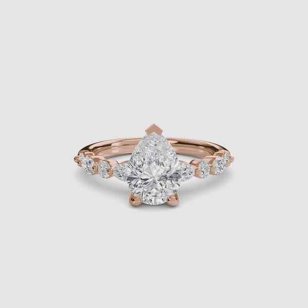 Rose gold ring with pear-shaped diamond on a white background