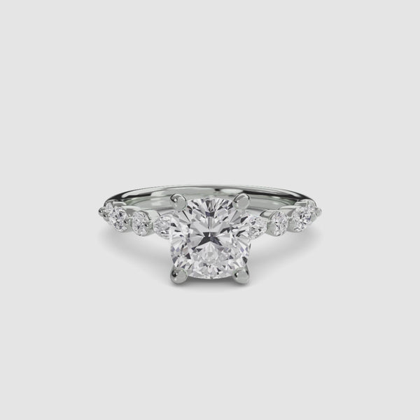White Gold ring with a large cushion cut diamond and smaller marquise shaped and round cut diamonds on the band against a white background