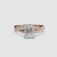 Rose gold ring with a large emerald-cut diamond and smaller diamonds on the twisted band against a white background