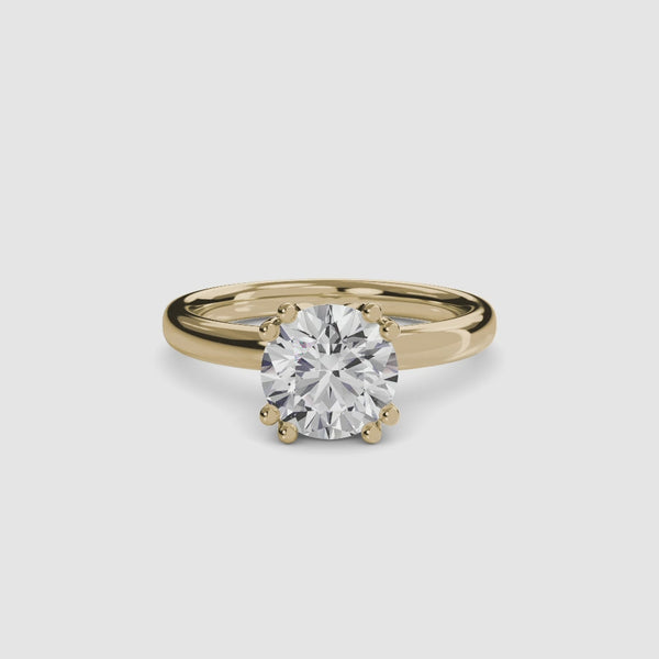 Top-down view of a yellow gold solitaire engagement ring featuring a large round brilliant-cut diamond secured by eight ball-tipped prongs in a floral basket setting, with a plain polished band 2.6mm.