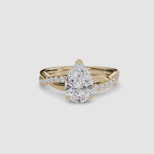 Gold ring with a pear-shaped diamond twisted pave shank on a white background.