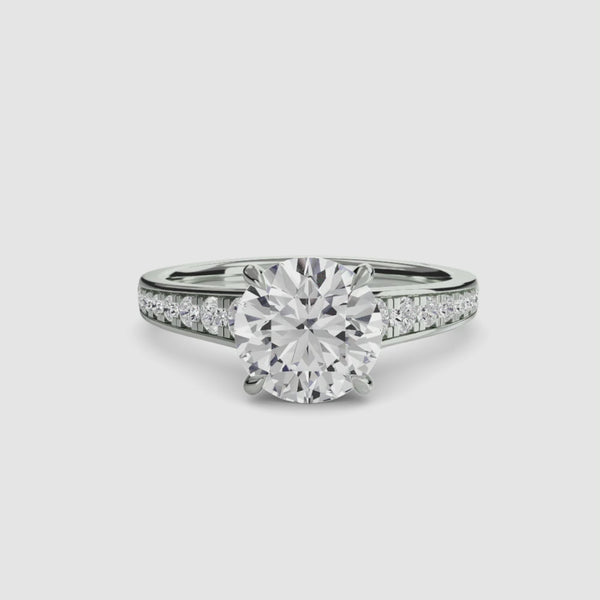 White gold ring with a large round diamond and smaller diamonds on the band against a white background