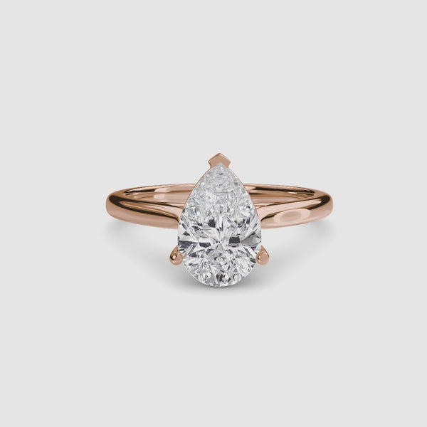 Rose gold ring with a pear-shaped diamond on a white background