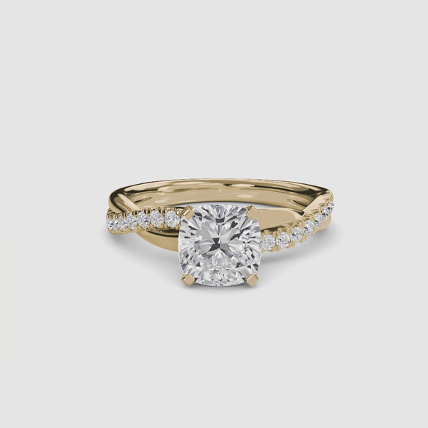 Gold ring with a large cushion-cut diamond and smaller diamonds on the twisted band against a white background