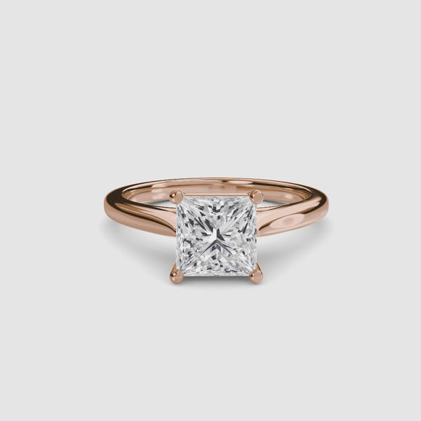 Rose gold solitaire ring with a large princess-cut diamond on a light gray background