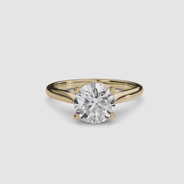 Gold solitaire ring with a round diamond brilliant cut on a white background