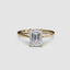 Solitaire gold ring with a large emerald-cut diamond on a white background