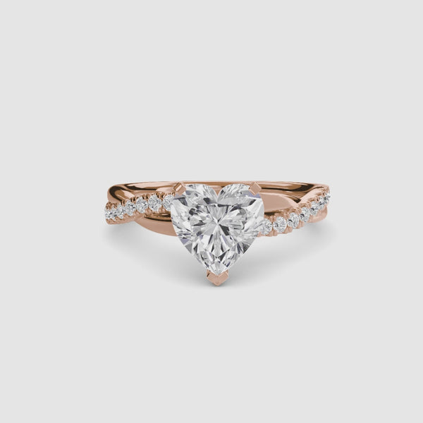 Rose gold ring with a heart-shaped diamond twisted pave band on a white background