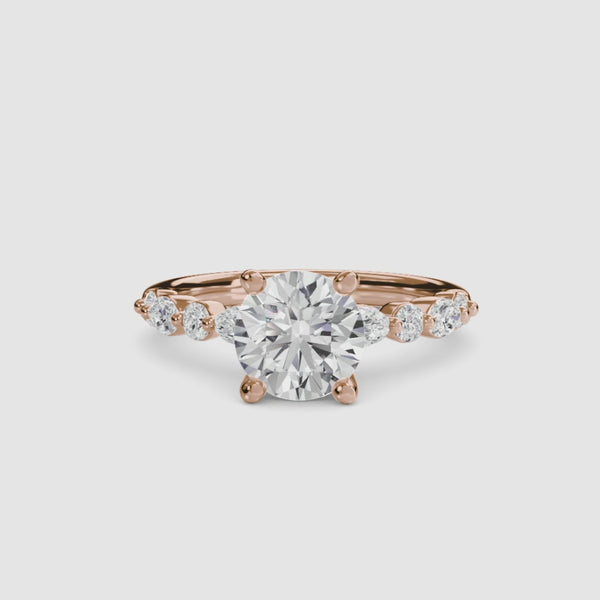 Rose gold ring with a large round diamond and smaller diamonds on the band against a white background