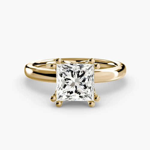Top-down view of a yellow gold solitaire engagement ring featuring a large princess-cut diamond secured by eight ball-tipped prongs in a floral basket setting, with a plain polished tapered band.