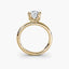 Front-facing view of a yellow gold solitaire engagement ring with a round diamond in an eight-prong tulip basket setting, showcasing the open gallery and plain rounded band against a light gray background.